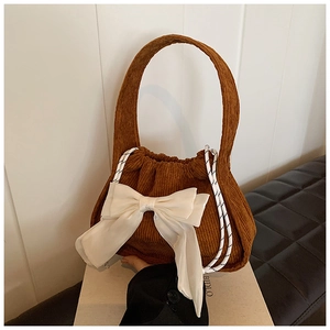 Détail d'un sac à main en velours côtelé marron avec gros nœud blanc et cordons tissés