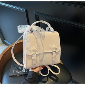 Close-up of pink leather backpack featuring white lace bow and butterfly buckles