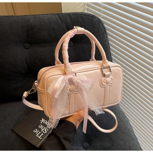 Detail of pink glossy handbag with lace ribbon, bow hardware and embossed character design