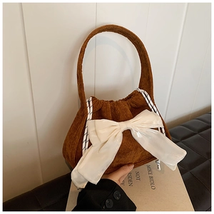 Détail de la texture en velours côtelé marron avec un grand nœud décoratif en satin crème