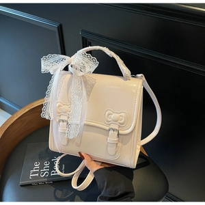 Detail of creamy white leather backpack featuring lace bows and relief buckle accents