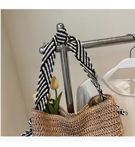 Détail du cabas en paille tressée avec poignées en tissu rayé noir et blanc nouées