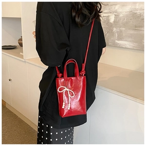 Vue détaillée d'un sac à main rouge avec pendentif nœud en perles et double poignée