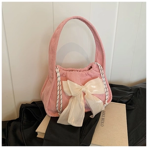 Détail d'un sac à main en velours côtelé rose avec un grand nœud décoratif en satin blanc
