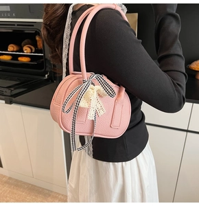 Dettaglio borsa a mano rosa in pelle PU con pizzo e fiocco a scacchi su modella