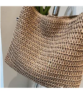 Gros plan sur la texture tissée ajourée complexe d'un sac cabas en paille d'été brun