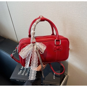 Detail of red patent leather square bag with lace bow and plaid scarf on a vintage chair