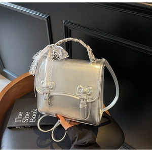 Detail of silver metallic bag with lace-wrapped handle and decorative metal bow