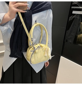 Dettaglio della borsa in pelle martellata giallo chiaro con fiocco a scacchi e pizzo floreale