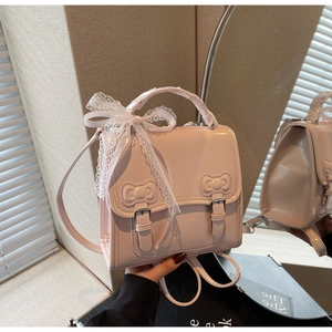 Detail of pink glossy leather backpack with decorative bows and white lace handle