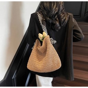 Détail du sac cabas en paille avec bandoulière rayée et décor de tulipe sur modèle