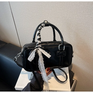 Detail of mini black bowling bag featuring white lace ribbons and bow on handles