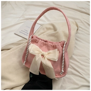 Detail of pink corduroy handbag featuring a large cream satin bow and side rope accents