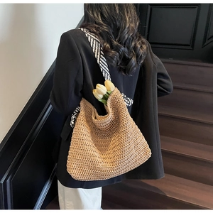 Détail d'un sac cabas en paille tressée avec bandoulière rayée et décor de tulipes
