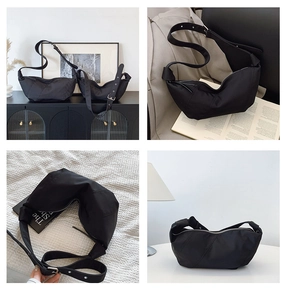 Detail of black pleated dumpling bag showing adjustable wide strap and silver metal buckle