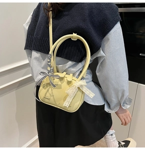 Dettaglio della borsa gialla ovale con nastro a quadretti decorativo e accenti in pizzo