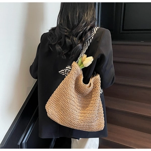 Détail d'un sac cabas en paille avec des bretelles rayées porté par un mannequin