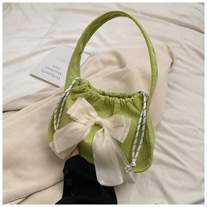 Detail of green corduroy drawstring bag with a large white organza bow on white fabric