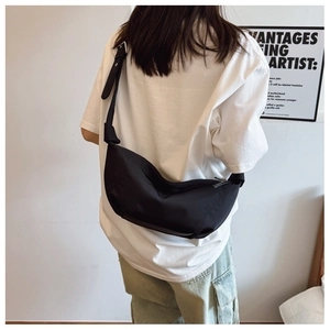 Detail view of the black nylon crescent bag silhouette shown on a model's shoulder