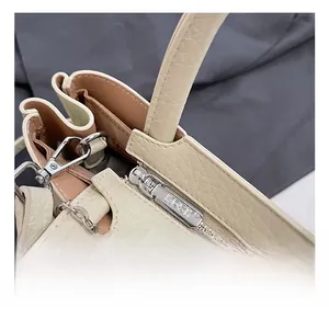 Detailed close-up of premium gold zipper and D-ring on cream pebble leather bucket bag