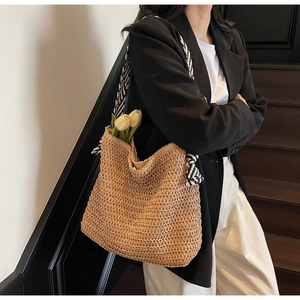 Détail d'un sac cabas en paille tissée avec des bandoulières en corde à rayures noir et blanc
