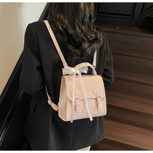 Rear view of a pink leather mini backpack with lace bow and metal buckle on model