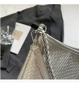 Detail of silver woven bucket bag with metallic texture and sleek chain strap