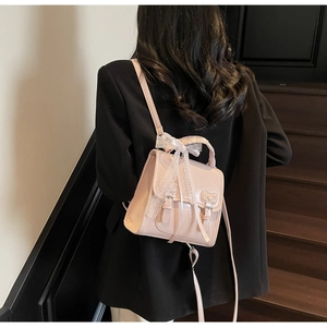 Pink PU leather backpack featuring lace bow details and double buckles for women