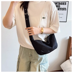 Detail of the black crescent dumpling bag showing stitching and wide strap on model