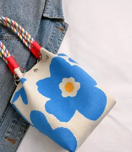 Detailopname van blauw-witte gebreide bucket bag met gevlochten handvatten