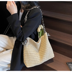Détail d'un sac cabas en paille beige avec bandoulières en corde tressée noire et blanche