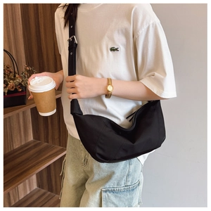 Detail view of the black oversized pleated dumpling bag worn by model on shoulder