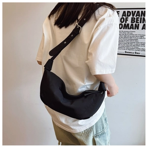 Side view of woman wearing a black pleated slouchy dumpling bag with adjustable strap