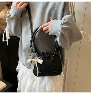Dettaglio borsa nera in pelle a grana con foulard a righe e fiocco di pizzo elegante
