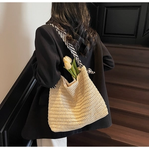 Détail d'un sac cabas en paille avec des bretelles à rayures noires et blanches