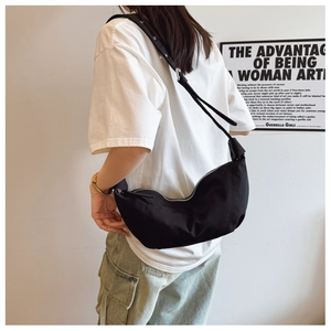 Detailed view of the black large pleated crescent bag worn by a model in casual style