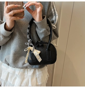 Dettaglio borsa bowling in pelle nera con eleganti fiocchi in pizzo e motivo a scacchi