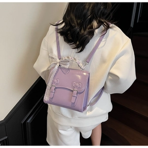 Macro detail of purple patent leather mini backpack with bow and lace ribbon details