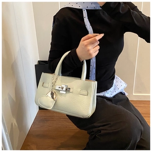 Close-up of light green lychee textured leather handbag with silver clasp and heart charm