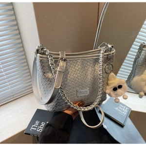 Detail of silver woven shoulder bag with metal plate and fluffy monster pendant