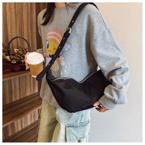 Detailed view of large black slouchy crescent shoulder bag with silver zipper on model