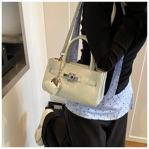 Close-up of mint green leather bucket bag with silver clasp and heart pendant