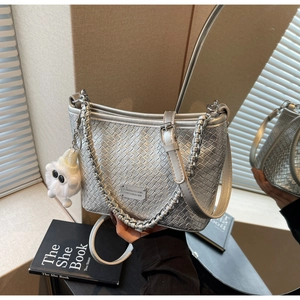 Detail of silver woven texture bag with metallic finish and cute plush charm accessory