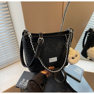 Detail of black woven leather shoulder bag with silver chain and white plush charm
