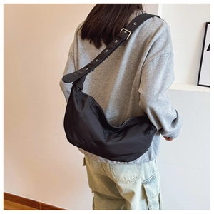 Side view of black crescent bag with adjustable eyelet strap on a model's shoulder