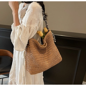 Détail d'un sac cabas en paille tissée avec une bandoulière à motif noir et blanc décoratif