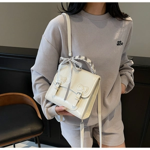 Detail of cream vintage crossbody bag with embossed bows and lace ribbon handle