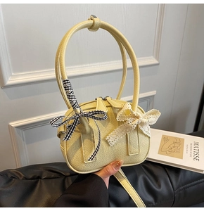 Dettaglio della mini borsa in pelle giallo crema con fiocchi in pizzo e a quadretti