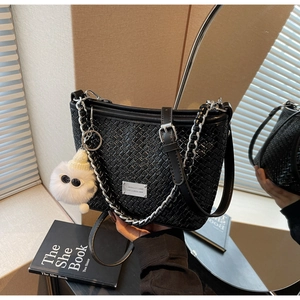 Detail of woven faux leather baguette bag with silver chain and white plush charm