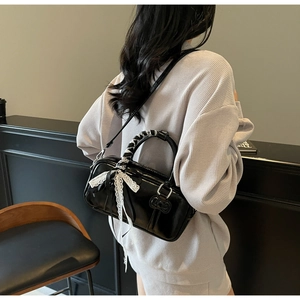 Detail of black patent leather mini Boston bag with lace bow and silk scarf wrap